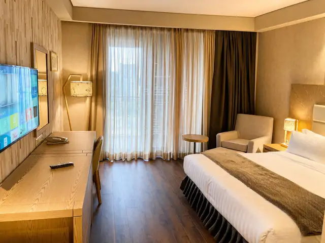 Bedroom with daylight through sheer curtains and warm wood flooring