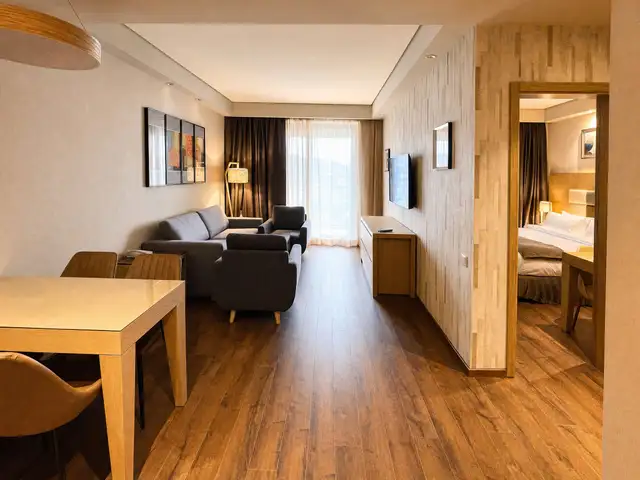 Living area with sofa and armchairs, opening to a separate bedroom