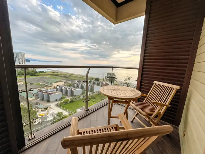 Studio Sea View & Mountain — Wooden balcony seating with sunset view over the resort and the sea