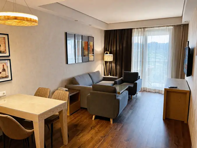 One Bedroom Sea View & Mountain — Living room with sofa, armchairs, dining table and balcony window One Bedroom Sea View & Mountain — Living room with sofa, armchairs, dining table and balcony window