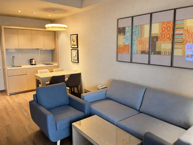 One Bedroom Sea View & Mountain — Open-plan living room with blue sofa, dining table and kitchenette One Bedroom Sea View & Mountain — Open-plan living room with blue sofa, dining table and kitchenette