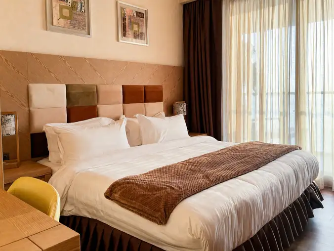 One Bedroom Sea Front & Pool View — Bedroom with king bed and patchwork upholstered headboard