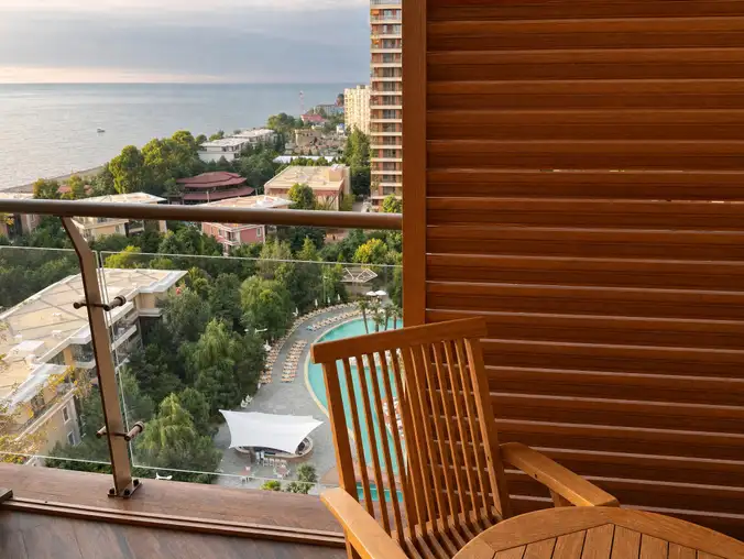 One Bedroom Sea Front & Pool View — Balcony seat at sunset with sea horizon and pool gardens below