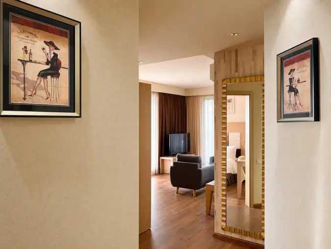 One Bedroom Sea Front & Pool View — Hallway with framed art and full-length mirror reflecting the lounge