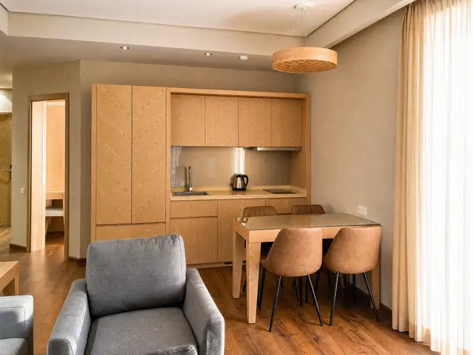 One Bedroom Sea Front & Pool View — Kitchenette with oak cabinetry, dining table and a lounge corner
