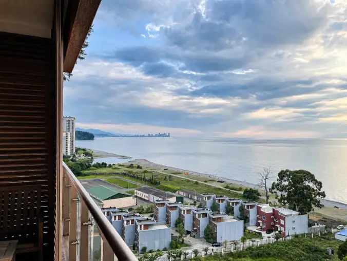 One Bedroom Sea Front & Batumi Side — Wide sea view with low-rise resort homes and Batumi skyline in the distance