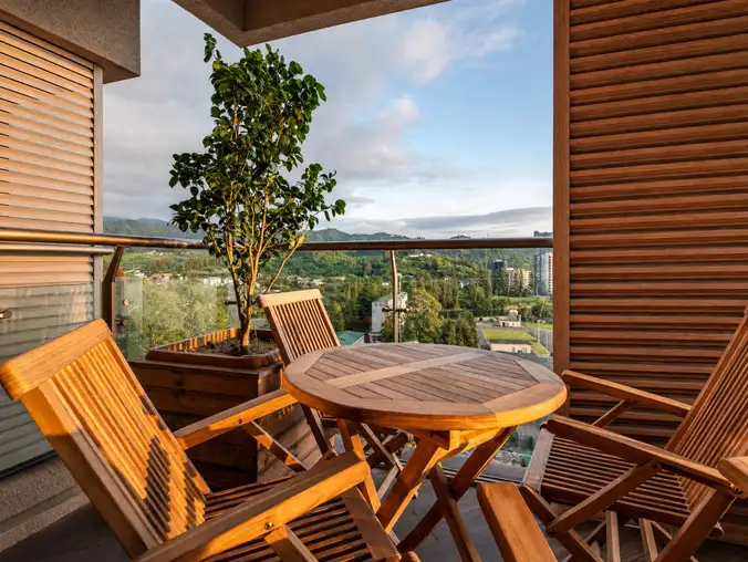 One Bedroom Sea Front & Batumi Side — Terrace with wooden chairs, potted tree and a green mountain view
