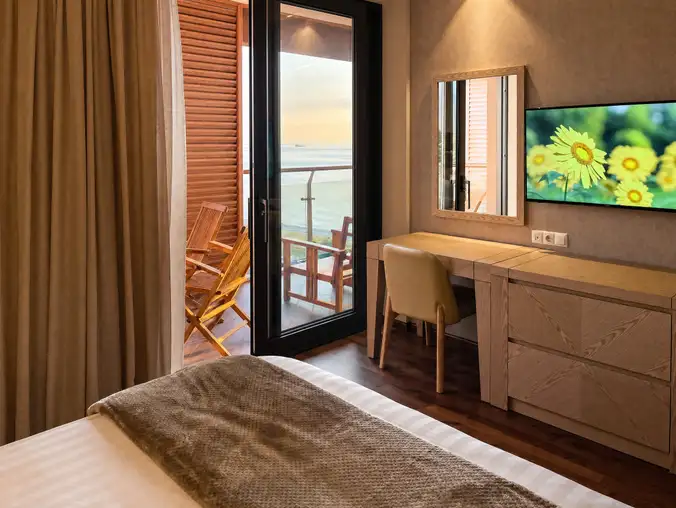 One Bedroom Sea Front & Batumi Side — Bedroom with vanity, mounted TV and balcony opening to a sea view