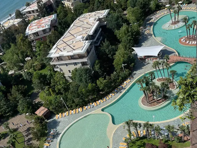 One Bedroom Sea Front & Batumi Side — Aerial view of resort lagoon pools and aquapark from the apartment
